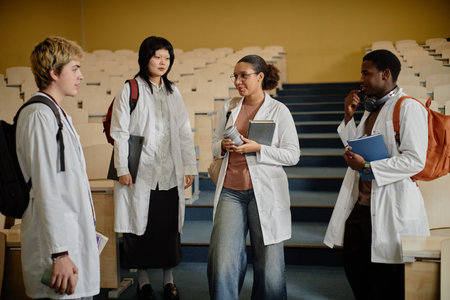 Wide angle shot of diverse group of med students standing and talking in empty lecture hall before class in collegeの写真素材