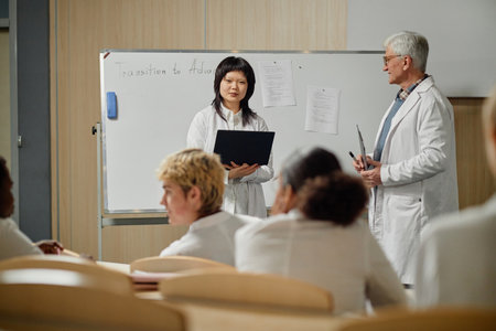 Portrait of Asian female med student standing by whiteboard and presenting topic while senior professor observing, copy spaceの写真素材