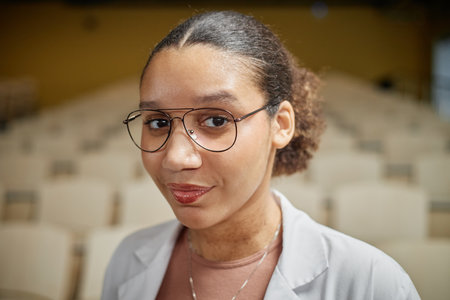 Vertical portrait of young African American med student standing in empty college lecture hall, copy spaceの写真素材