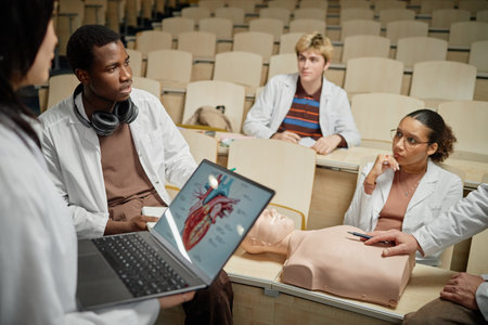 Side view of African American med student listening to professor during CPR training in classroomの写真素材
