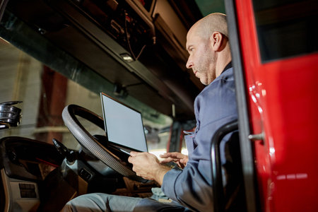 Professional truck driver using onboard technology in cab of red truck. Inside view of trucks cab with driver engaged in transportation-related taskの写真素材