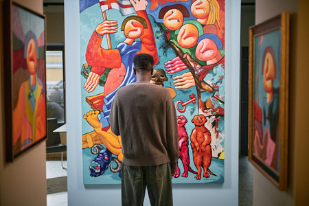 Individual standing in art gallery closely examining vibrant abstract painting filled with various...