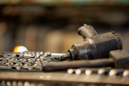 Close-up capturing various automotive tools in a mechanics workshop. Showing used nuts and bolts alongside a pneumatic wrench, conveying theme of repair and maintenanceの写真素材