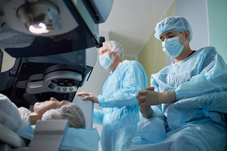 Asian man wearing surgical mask and gloves assisting during medical procedure in operating room...