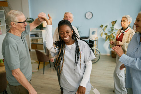 Group of senior residents and caregivers celebrating in an assisted living facility. People sharing smiles and joyful expressions, creating a positive atmosphere in common areaの写真素材