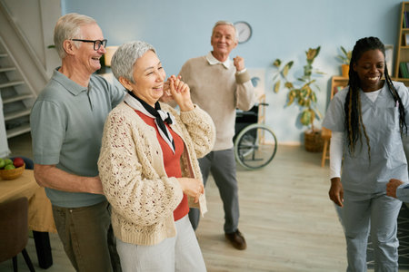 Group of seniors enjoying happy conversation with caregiver in cozy living room setting. Warm atmosphere bringing joy to elderly people as they engage in social interactionの写真素材