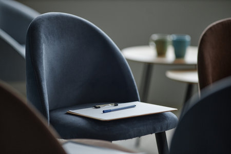 Empty chair with clipboard and pen resting on seat in counseling session setting, blurred background...