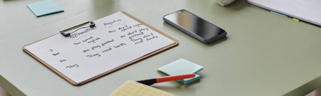 Website header shot of clipboard with handwritten English grammar notes lying on desk near...