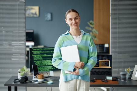 Portrait of young adult Caucasian woman smiling and looking at camera while standing in modern...