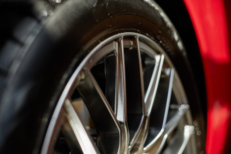 Close up showing car wheel rim with detailed tire tread, capturing metallic spokes and rubber...