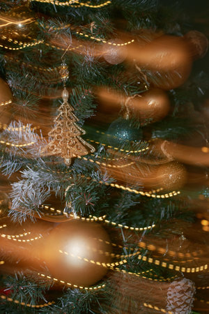 Closeup showing decorated Christmas tree with gold and green ornaments, glittering baubles, pine cones, and sparkling lights creating festive holiday atmosphereの写真素材