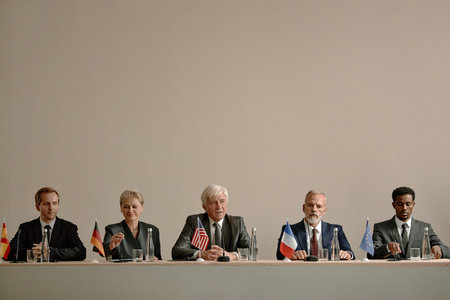 Group of middle aged and senior multiethnic men and women sitting at conference table holding...