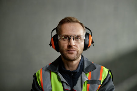 Portrait of Caucasian middle aged man wearing safety glasses and noise cancelling headphones,...