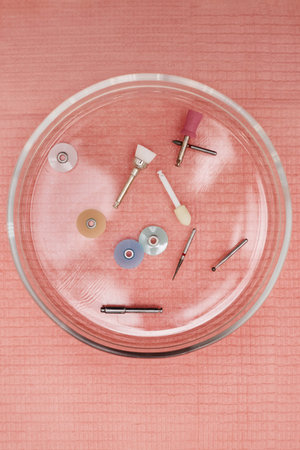 Dental polishing and cleaning tools arranged in glass dish on textured surface, showing various...