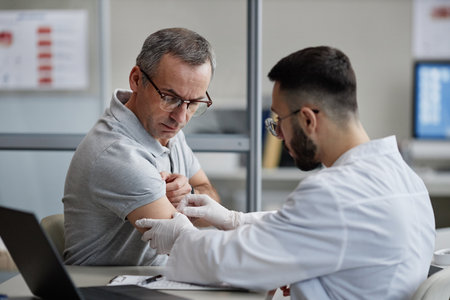Middle aged Caucasian man receiving skin examination from young adult male dermatologist wearing...