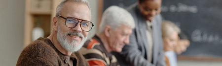 Website header shot of smiling senior Caucasian man looking at camera while sitting in classroom...