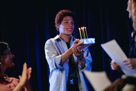 Diverse students celebrating birthday during theater rehearsal on stage. Image ideal for promoting youth drama clubs, extracurricular activities, and creative student collaboration