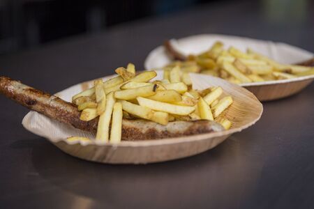 Bratwurst with french fries on a bamboo plateの写真素材