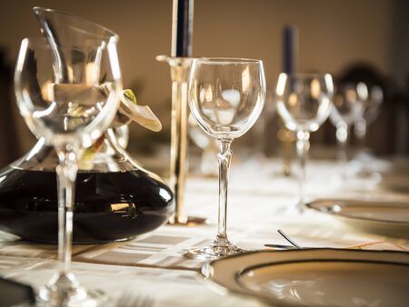 A table with wine glasses, dishes and plates for a celebration.の写真素材