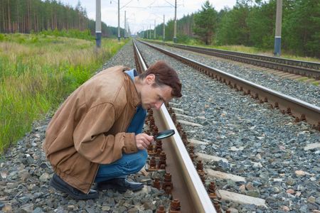Man sits on railway and with enthusiasm examines somethingの写真素材