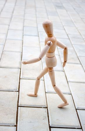 Wooden little man walks on stone pathの写真素材