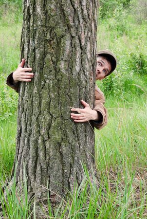 Man hugging tree with fear on faceの写真素材