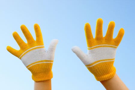Two hands dressed in gloves against the skyの写真素材