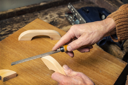 Carpenter working in a workshop rasp, makes furniture handles