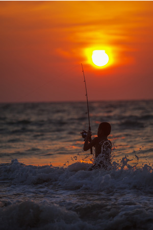 PHUKET, THAILAND - CIRCA MAR 2013: Thai fisher boy, fishing during the twilight sunset in the Andaman Sea. Thailandのeditorial素材