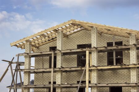 Wooden roof on a brick house under construction during mountingの写真素材