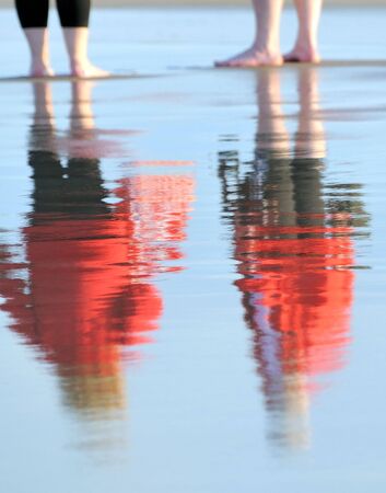 Reflexion of figures of two people on wet sand. Coast of the Baltic sea. Eveningの写真素材