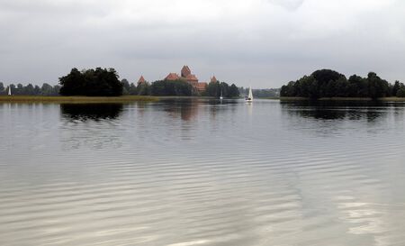 Lake and castle in summer cloudy day. Yachts on waterの写真素材