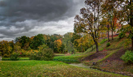 Beautiful park near renaissance Panemune castle. Maple trees at a autumn color. Mellow autumn. Old pond, water covered dry foliage. Vytenai, Jurbarkas district municipality, Lithuania.の写真素材