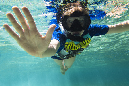Teenager in a mask and a tube under the waterの写真素材