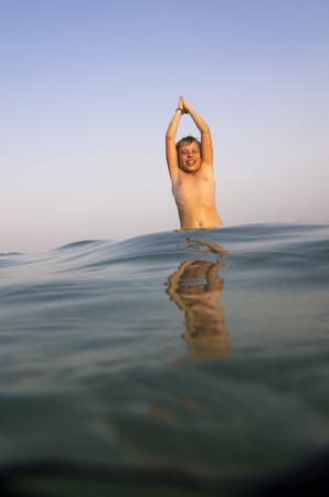 Teenager to develop in the oncoming sea waveの写真素材