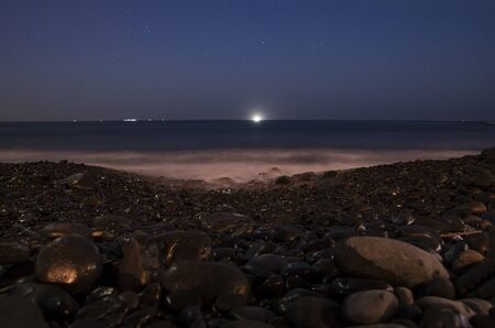 Night landscape of the sea coast with black pebblesの写真素材
