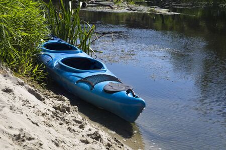 Kayak on the sandy shore of a small riverの写真素材