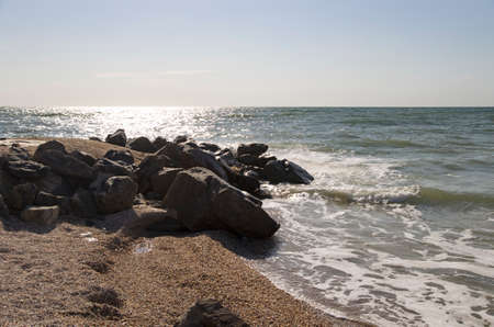 Stone boulders on the sandy spit of the sea coastの写真素材