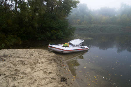 Inflatable boat on the bank of a misty river in autumnの写真素材