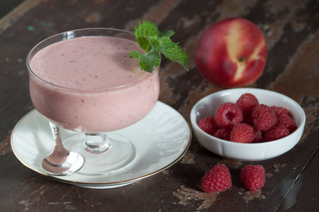 Smoothies of raspberries and nectarines with yogurt in a glass on a wooden tableの写真素材