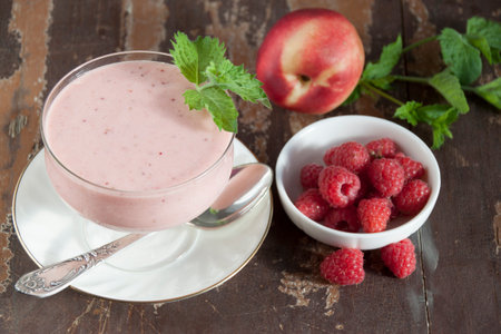Smoothies of raspberries and nectarines with yogurt in a glass on a wooden tableの写真素材