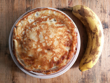 A pile of banana pancakes with honey on a plate a vi banana on an old wooden tableの写真素材