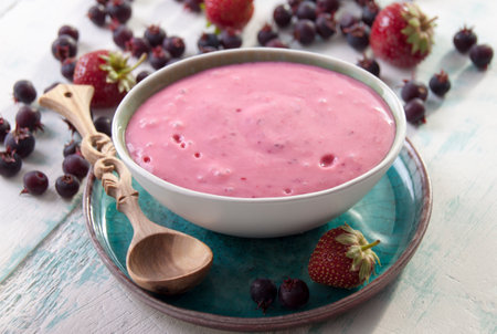 Smoothies of strawberries and irgi with yogurt in a ceramic bowl and berries irgi and strawberries on a tableの写真素材
