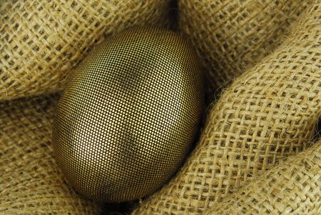 golden easter egg on hessian texture の写真素材