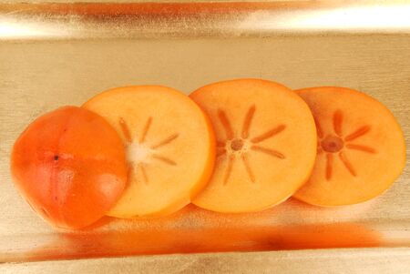 persimmon fruit  slices  on the golden plateの写真素材