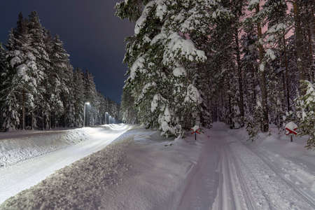 Selective focus of Snowmobile tracks and Heavy snow-covered and plowed walkway illuminated with street light in Pitea City in northern Sweden, Europe.の写真素材
