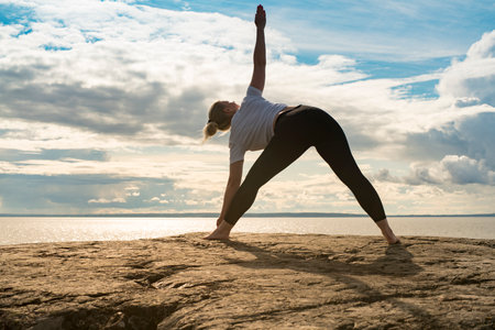 Woman practicing Yoga, meditation or stretching close to water on Cliff doing different poses on...