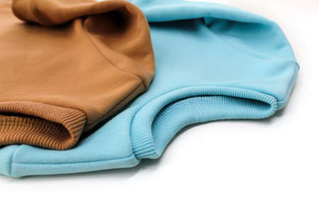Two sweatshirts of blue and ochre color are close-up.