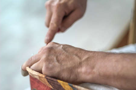 The workflow of restoration of upholstered furniture. Overworked male hands remove the old...
