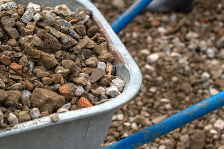Trolley for building material. Distribution of rubble on the road. Concept: construction, road repairs, sale of crushed stone, backgrounds and textures, working tools.の写真素材